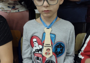 Chłopiec w okularach w krawacie z napisem "Super chłopak."